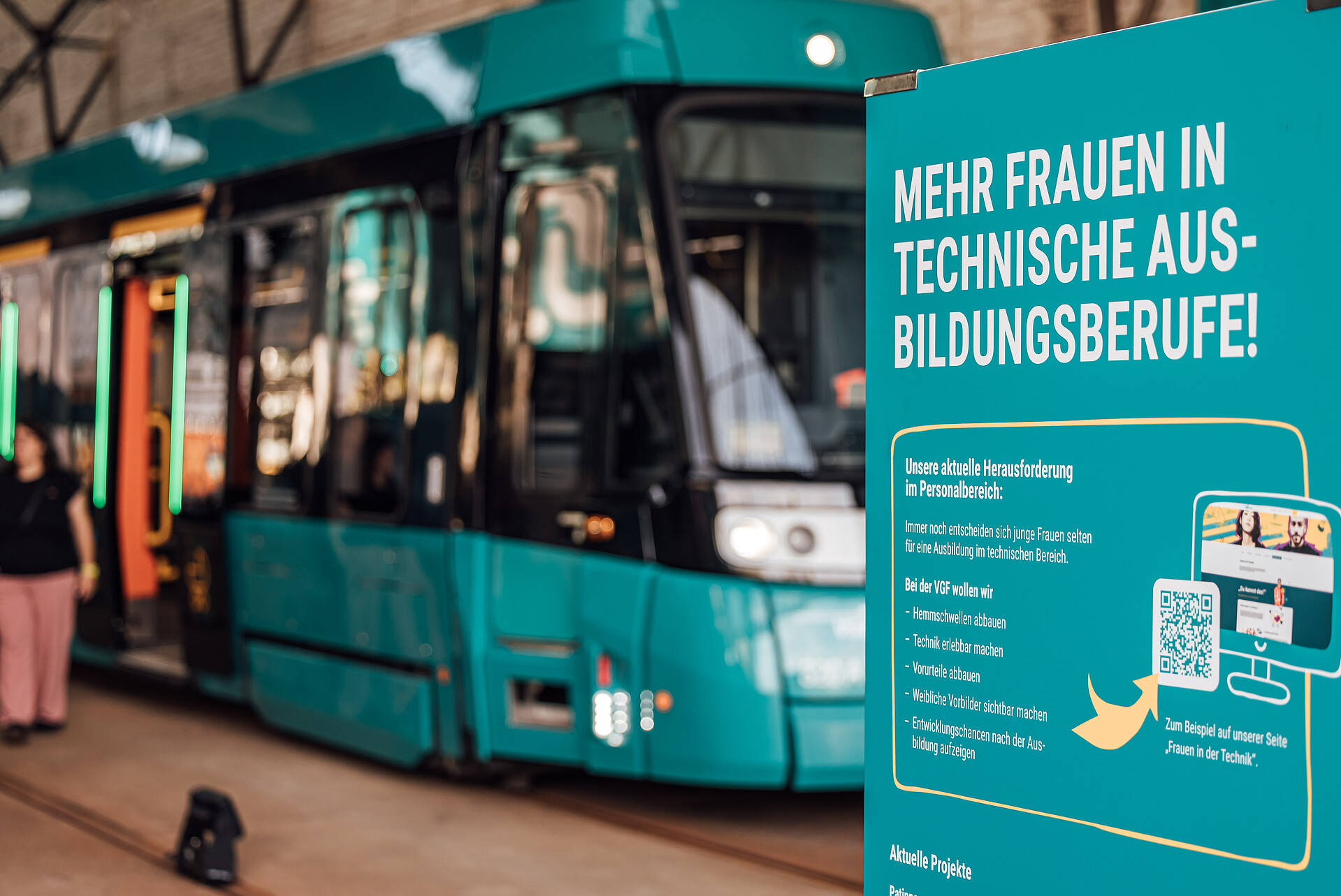 Mehr Frauen in technische Ausbildungsberufe-Plakat, im Hintergrund ein Straßenbahnwagen der VGF