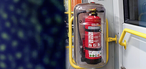 Das Bild zeigt einen Feuerlöscher in einem Fahrzeug.