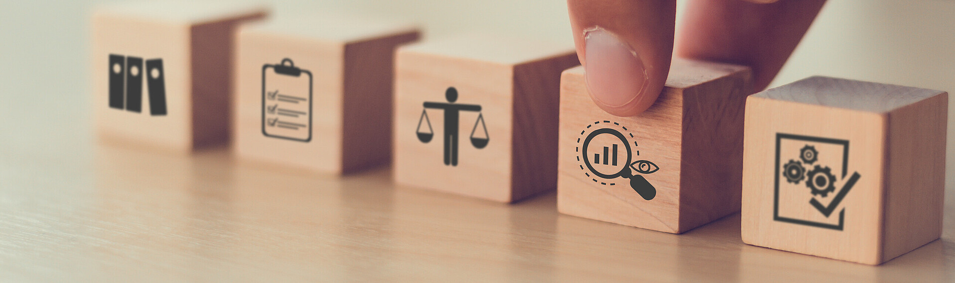 Fünf Holzwürfel mit verschiedenen Motiven drauf wie Lupe, Mensch mit Waage und Ordner-Symbol