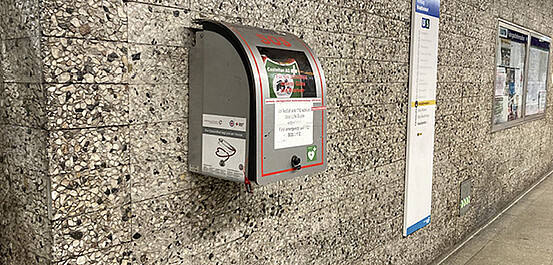 Das Bild zeigt einen Defibrillator an der Wand einer U-Bahnstation.